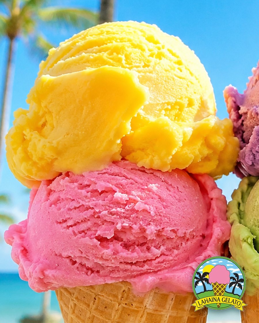 Mango and strawberry gelato stacked on a waffle cone
